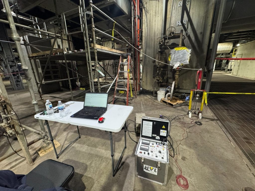 Technicians performing a DC leakage and hipot test on a 500 MW liquid-cooled generator stator, showing the test equipment connected to the stator windings inside a power plant.